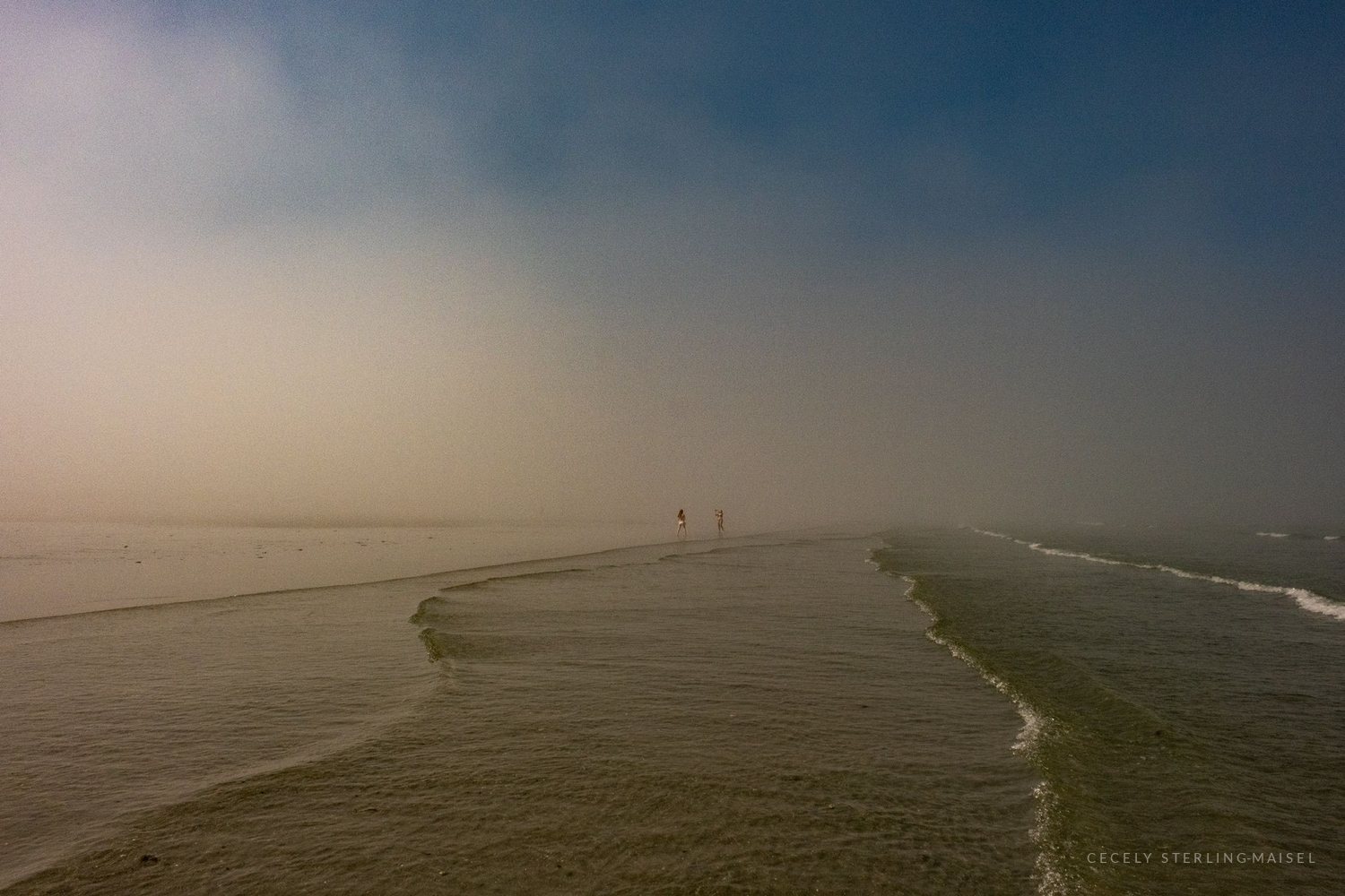 A long breakwater curving out into dense fog until the horizon disappears entirely.